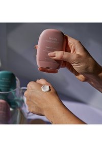 Crema de manos HAAN, envase rosa, dispensando crema sobre una mano. Textura suave, grosor medio, etiqueta clara con el nombre del producto y detalles.