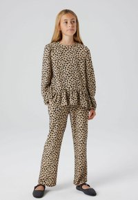 Ensemble de pyjama imprimé léopard comprenant un haut à manches longues avec un ourlet volanté, associé à un pantalon droit en beige avec des taches noires.