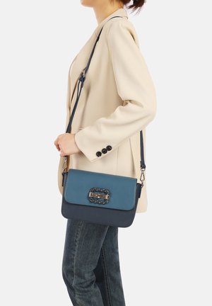 Borsa a tracolla in pelle verde acqua e blu navy con una fibbia intrecciata in argento. Presenta una lunga tracolla regolabile e una forma rettangolare strutturata.