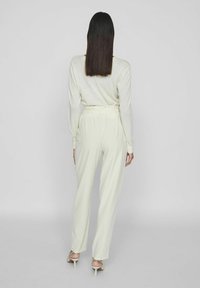 Heled kollane pika varrukaga särk, millel on mugav lõige, koos vastava laiade pükstega, millel on vööga talje ja sile kangast tekstuur.