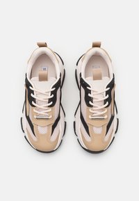 Sneakers with a mesh upper, features black, beige, and white sections. Thick sole with textured accents and a lace-up front.
