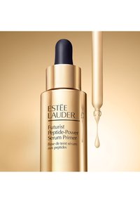 Gul cylindrisk flaske med sort dråbehætte. Teksten på flasken inkluderer "Estée Lauder Futurist Peptide-Power Serum Primer." Klar serumdråbe.
