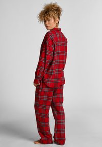 Roter karierter Flanell-Schlafanzug mit langen Ärmeln, Knopfverschlusshemd und passenden Hosen mit lockerer Passform und blauen Akzenten im Muster.