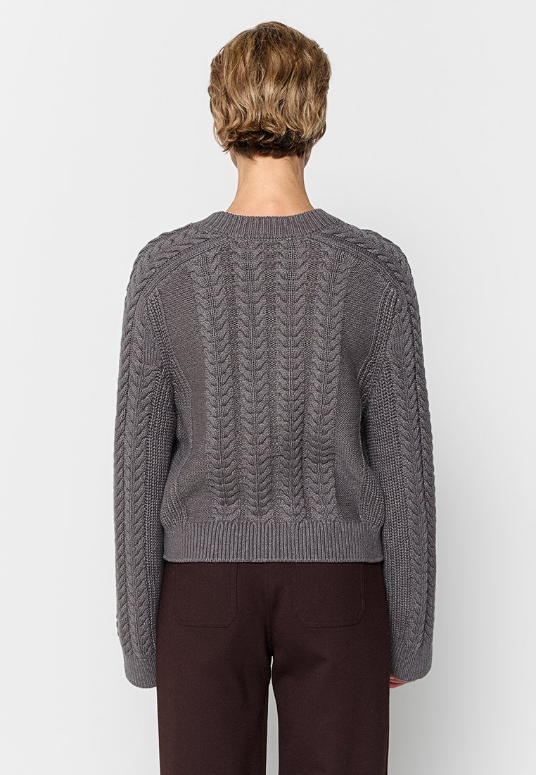 Pull en maille grise avec un ourlet côtelé et des manches texturées, présentant un col rond et un design court.
