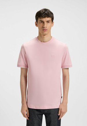 T-shirt rosa a maniche corte con scollatura rotonda, texture morbida e logo discreto sul petto. Abbinato a jeans in denim scuro.