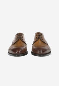 Chaussures habillées en cuir avec une finition bicolore en marron foncé et tan, au design classique, bout rond et fermeture à lacets à cinq œillets.