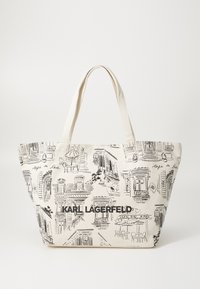 Tote torba od bež kanvasa, s crnim skicama zgrada i scena kafića. "KARL LAGERFELD" istaknuto otisnuto na prednjoj strani.