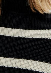 Pull à col roulé en maille présentant des rayures horizontales bleu marine foncé et crème. Tissu texturé, col côtelé et bords soigneusement finis.