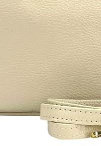 Beige leren tas met een gestructureerd oppervlak, voorzien van een lichte schouderband en gouden hardware accenten. Het ontwerp benadrukt eenvoud en elegantie.