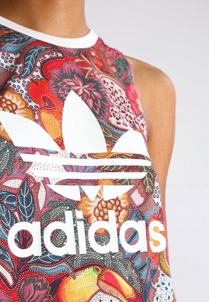Nahaufnahme eines ärmellosen Oberteils mit einem bunten Blumen- und Vogelmuster sowie einem großen weißen Adidas-Logo auf der Brust.