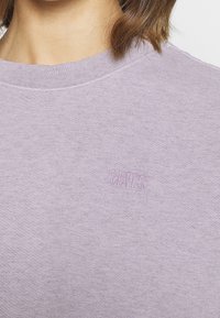 Lavender sweatshirt featuring a crew neck, ribbed cuffs, and subtle embroidered "Levi's" logo in the same color. Soft cotton fabric texture.
