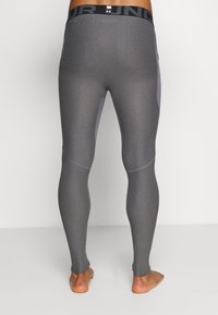 Leggings de sport gris avec une coupe près du corps, dotés d'une taille élastique noire, d'une texture lisse et de panneaux latéraux contrastants dans une teinte plus claire.