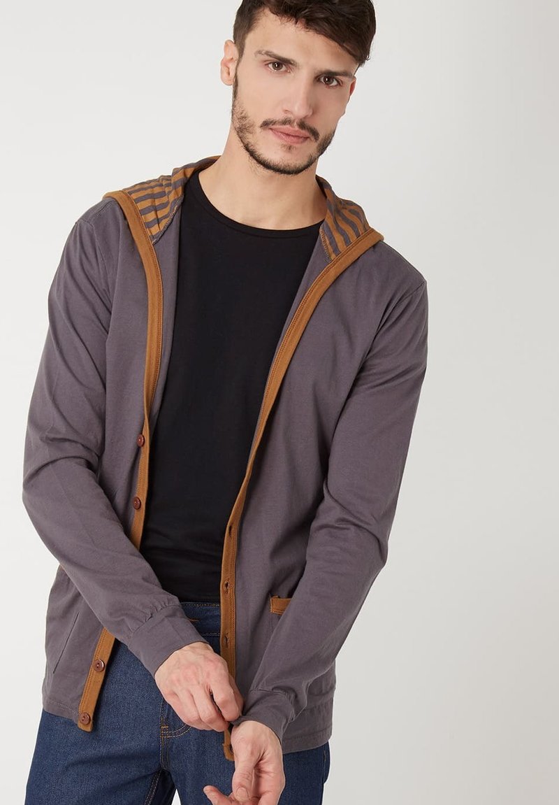 Sudadera gris con acentos marrones y forro interior a rayas. Cuenta con botones en el frente y dos bolsillos laterales. Material casual de mezcla de algodón.