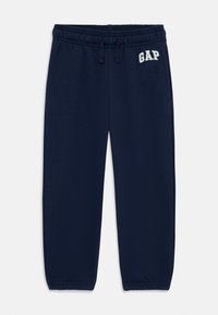 Laivansiniset collegehousut, joissa on elastinen vyötärö, nyöri ja valkoisella kirjailtu "GAP"-logo. Pehmeä kangas ja rento istuvuus.