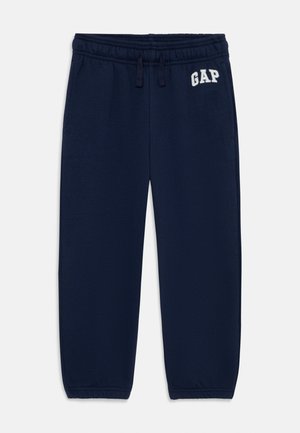 Temno modri trenirki z elastičnim pasom, vrvico in izvezenim logotipom "GAP" v beli barvi. Mehka tkanina z sproščenim krojem.