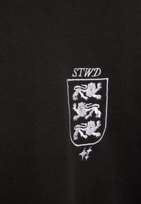 Fekete szövet fehér hímzett címerrel, melyen három oroszlán és a "STWD" betűk láthatók felette.