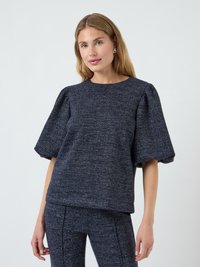 Marineblaues, strukturiertes Oberteil mit kurzen Puffärmeln und rundem Ausschnitt, kombiniert mit passenden, figurbetonten Leggings. Aus weichem, gewebtem Stoff.