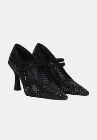 Zapatos de tacón alto negros con punta afilada, parte superior texturizada con tachuelas similares a diamantes, dos correas estrechas sobre el empeine y detalles de ante.