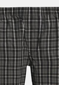 Grau karierte Boxershorts mit einem schachbrettartigen Muster, das schwarze, dunkelgraue und weiße Linien enthält. Elastischer Bund und weiche Stoffstruktur.