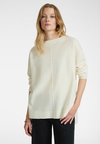 Cremfarbener Pullover aus weichem Stoff mit lockerer Passform, Bootsausschnitt, langen Ärmeln und einer Mittelnaht.