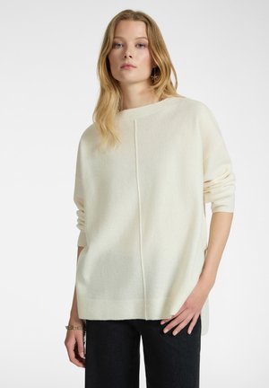 Crème-kleurige trui van zacht materiaal met een relaxte pasvorm, voorzien van een botte hals, lange mouwen en een centraal naaddetail.