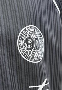 Tissu rayé noir et gris avec un logo circulaire blanc « 90 Core Creative Dept » et un petit signe graphique blanc en dessous.