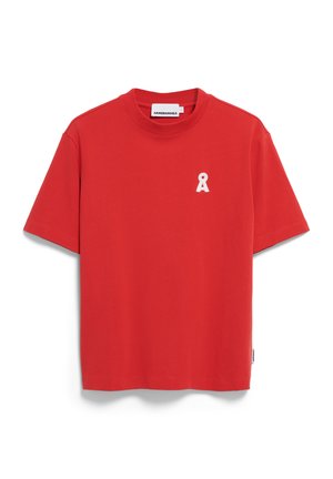 Camiseta de algodón roja con cuello redondo, mangas cortas y un pequeño logo de cinta blanca en el lado izquierdo del pecho. Textura suave, diseño casual.