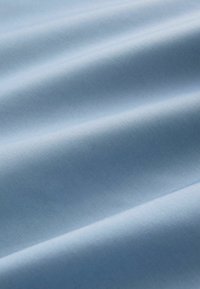 Helles blaues Gewebe mit einer glatten Textur, das subtile Wellen und ein einheitliches Webmuster aufweist. Das Material wirkt leicht und weich.