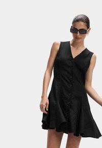 Abito nero con bottoni frontalmente, scollatura a V, orlo svasato e tessuto testurizzato, con sei bottoni sul davanti e senza maniche.