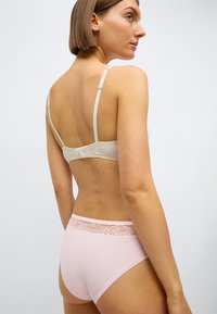 Světlé béžové podprsenka s nastavitelnými ramínky a zapínáním na háček; růžové kalhotky s vysokým pasem a krajkovým proužkem v pase. Hladká textura.