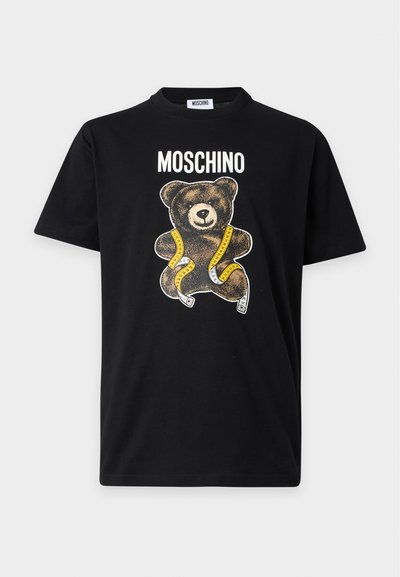 Μαύρο μπλουζάκι Moschino με γραφικό αρκουδάκι τυλιγμένο με κίτρινη μεζούρα και το όνομα της μάρκας τυπωμένο από πάνω.