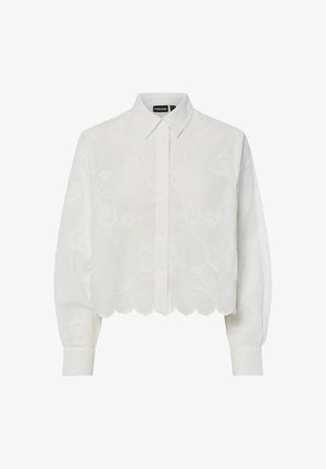 Blouse blanche courte avec un motif floral brodé, manches longues et ourlet festonné. Elle présente un col classique et une fermeture à boutons.