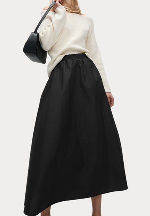 Zwarte enkellange rok met een geplooide tailleband, gecombineerd met een crèmekleurige gebreide trui en een zwarte handtas. Eenvoudig ontwerp, gladde textuur.