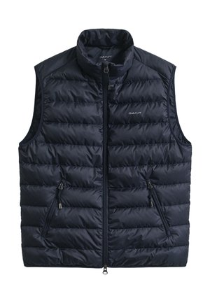 Tmavě modrá prošívaná vesta s vysokým límcem, předním zipem a dvěma kapsami na zip po stranách. Vyrobena z lehké tkaniny s prošívanou strukturou.