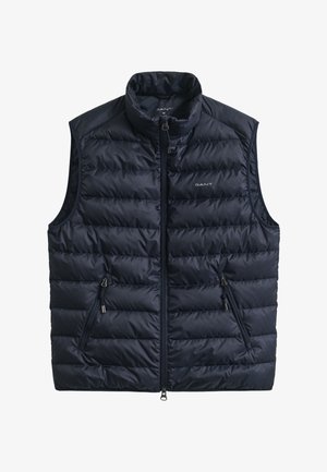 Veste matelassée bleu marine avec col montant, fermeture éclair frontale et deux poches latérales zippées. Conçue en tissu léger avec une texture matelassée.