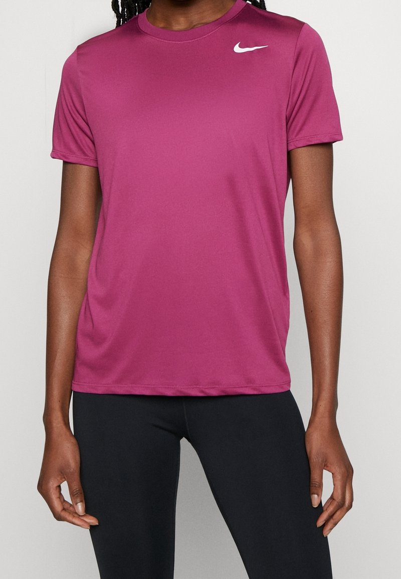 Short-sleeve athletic shirt in dark pink fabric, featuring a round neckline and a white Nike logo on the left chest, smooth texture.