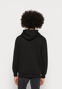 Felpa nera con tasca a marsupio, polsini e orlo a coste, caratterizzata da una texture morbida e un cappuccio foderato. Nessun motivo o accento visibile.