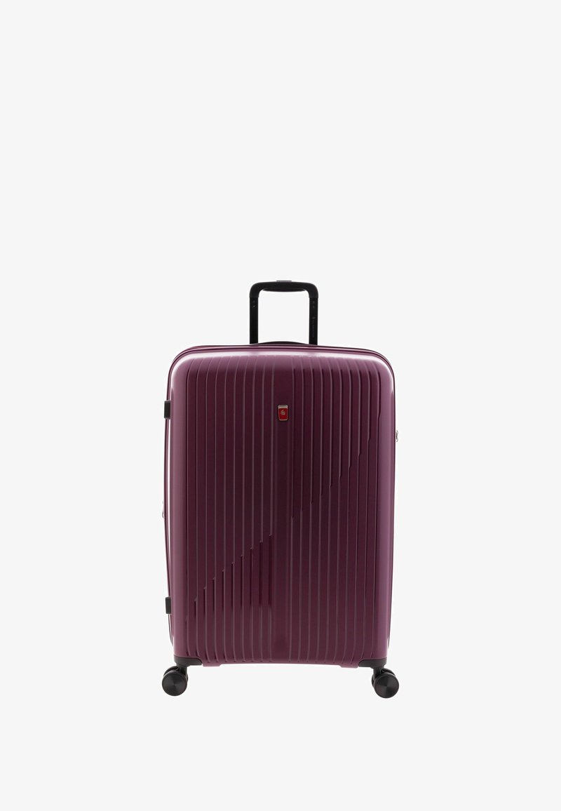 Valise rigide de couleur violette avec des rainures verticales, une poignée noire rétractable et quatre roues noires pour la mobilité.