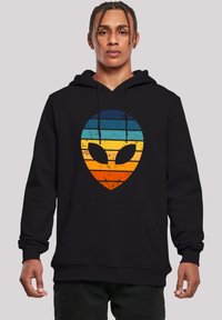 Schwarzer Hoodie mit einem großen Alienkopf-Graphic und horizontalen Streifen in Blau, Türkis, Orange und Gelb. Strukturiertes Finish.
