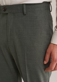 Graugrüne maßgeschneiderte Hose aus strukturiertem Stoff, mit flachem Vorderteil, Gürtelschlaufen und einem einzigen Knopfverschluss am Bund.