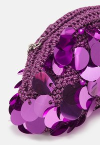 Borsa intrecciata viola con paillettes circolari lucide e reflective, superficie testurizzata e dettagli in metallo argentato. Forma compatta e rotonda.