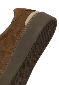 Sneaker in suede marrone con suola in gomma liscia e scura con un motivo a zigzag. Il bordo presenta un accento in un beige chiaro a contrasto.