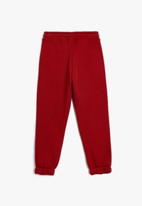 Rote Jogginghose aus weichem Material, mit einem elastischen Bund und Bündchen, für bequemes Tragen mit lockerer Passform.