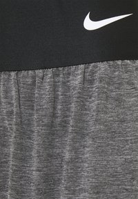 Zwarte tailleband met geplooide grijze stof eronder. Bevat een wit Nike-logo op de tailleband. Materiaal lijkt zacht en textuur te hebben.