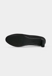 Chaussure noire à talon bas vue du côté de la semelle, avec des motifs décoratifs sur la semelle et un petit talon carré.