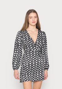 Vestido preto envolvente com padrão floral branco, decote V profundo, mangas longas de balão e um laço na cintura. Tecido suave com uma textura leve.