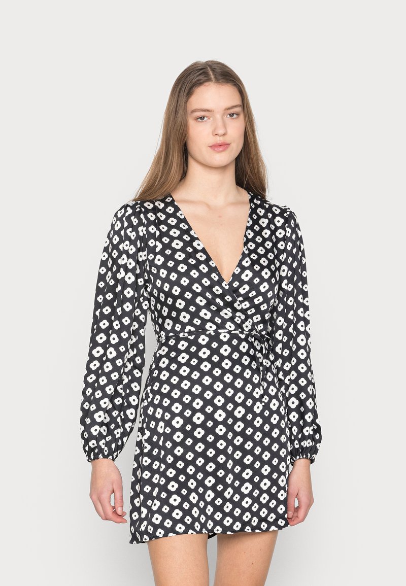 Vestido preto envolvente com padrão floral branco, decote V profundo, mangas longas de balão e um laço na cintura. Tecido suave com uma textura leve.