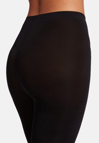 Svarta leggings med ribbat mönster, hög midja och en åtsittande siluett, som ger ett smidigt och flexibelt utseende.