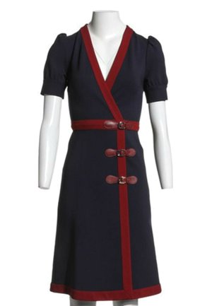 Marineblaues Kleid mit kurzen Puffärmeln, tiefem V-Ausschnitt, rotem Besatz, drei roten Schnallenverschlüssen und rotem Taillenbund auf einer weißen Schaufensterpuppe.
