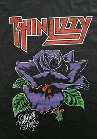 Svart t-skjorte med et stort motiv av en lilla rose med grønne blader, overlagt med rød tekst som leser "THIN LIZZY" og "Black Rose."